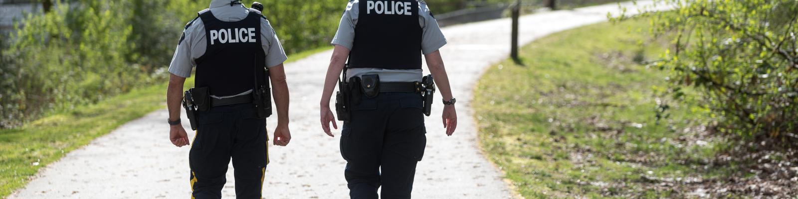 Two police officers walking down a trail