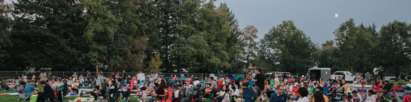 Crowd of people watching an outdoor movie at the park