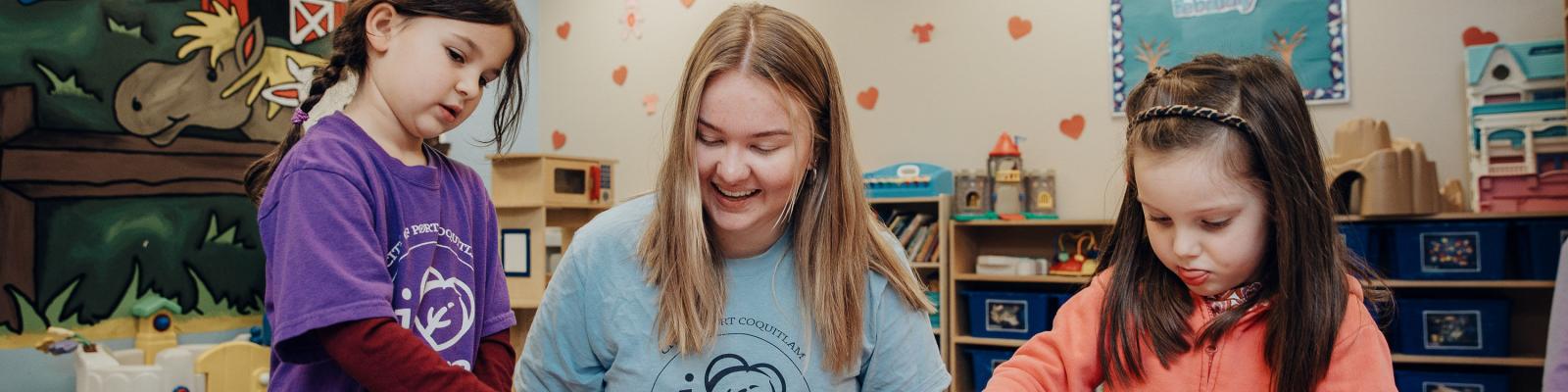 Camp leader and two kids doing crafts at a table