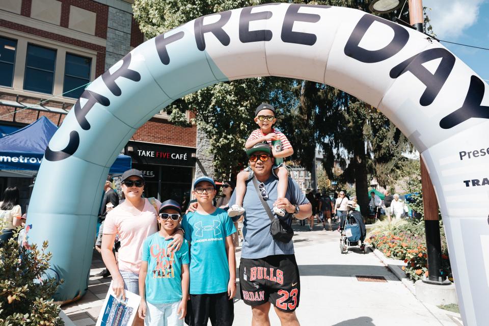 family in front of car free day arch