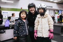 skating volunteer helping two children
